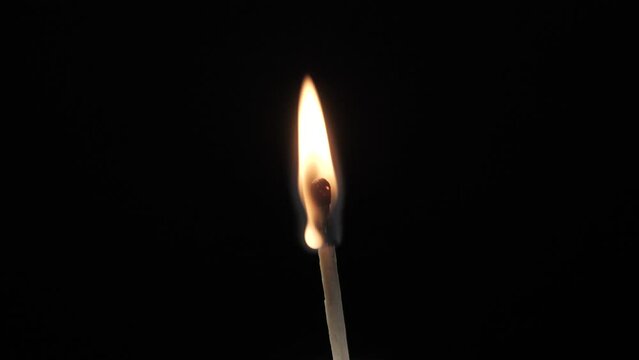 A burning match on a black background