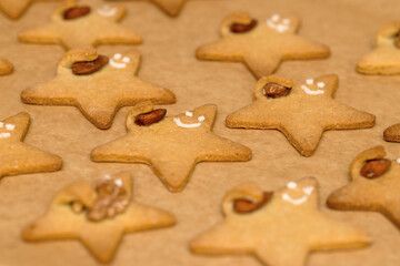 Baked funny cookies with faces with nuts in hand on a baking sheet close-up