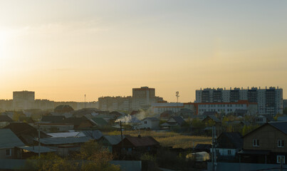 Obraz premium Evening landscape with village houses and multi-storey houses on the horizon sunset