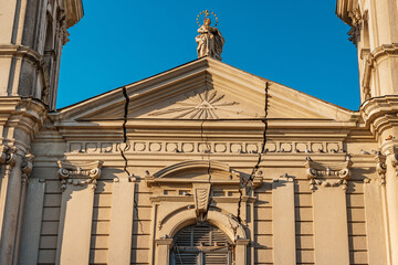 weathered facade of the church bears the scars of time, with cracks and fractures etched into its...