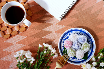 Coffee with Thai desserts for a relaxing time. Steamed flour with sweet coconut filling, it is a traditional Thai dessert called Khanom Tom. Dessert and flower decoration with a cafe-style concept.