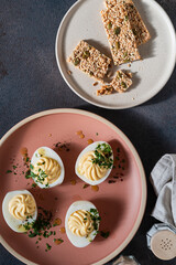 Deviled eggs with spicy oil and herbs, flatbread crackers, Easter party appetizer, directly above - 750797089