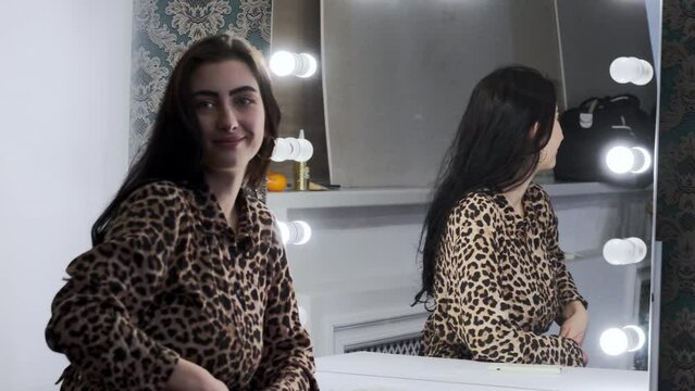 Attractive woman with long hair poses confidently taking photo. Self-confident female in leopard print dress capture reflection in mirror