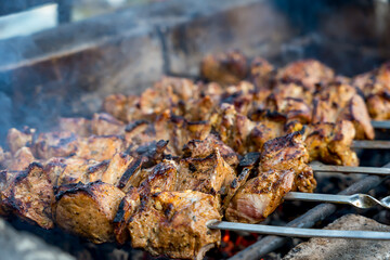Barbecue on the grill. Grilled kebab cooking on metal skewer, close up