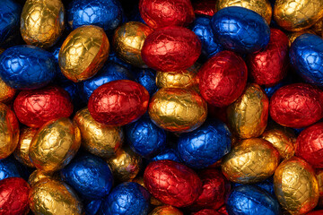 Fototapeta na wymiar Chocolate easter eggs in colorful tinfoil close up full frame as background