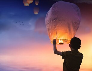 The man releases a paper lantern into the sky, its soft glow illuminating the darkness above. With...