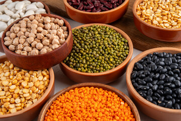 Various dried  beans, lentils, mung, chickpea, pea  assortment in wooden bowls. Legumes on white table top view. Vegan protein sources food, copy space