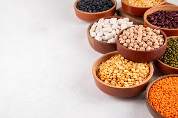 Various dried  beans, lentils, mung, chickpea, pea  assortment in wooden bowls. Legumes on white table top view. Vegan protein sources food, copy space