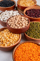 Various dried  beans, lentils, mung, chickpea, pea  assortment in wooden bowls. Legumes on white table top view. Vegan protein sources food, copy space
