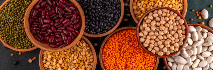 Various dried  beans, lentils, mung, chickpea, pea  assortment in wooden bowls. Legumes on white table top view. Vegan protein sources food, copy space