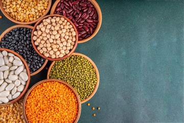 Various dried  beans, lentils, mung, chickpea, pea  assortment in wooden bowls. Legumes on white table top view. Vegan protein sources food, copy space