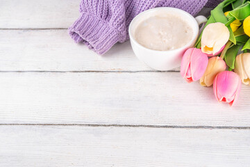 Spring morning with coffee background. A cup of coffee latte, lilac woman knitted sweater, a bouquet of tulips flowers. Spring holidays, holiday background, greeting card, top view flat lay copy space