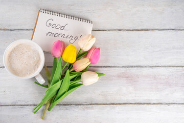 Spring morning with coffee latte cup background with Good morning note and bouquet of tulips...