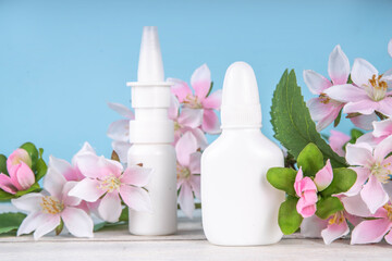 Seasonal spring allergies concept. Fresh spring blooming tree branches, various nasal allergy treatment, drops, spray bottles for allergies, rhinitis, pollinosi, copy space on colorful background