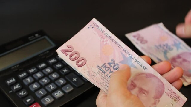 Hand of man counting Turkish money. Turkish lira banknotes. Paper currency of Turkey. 200, 100, 50 Turkish liras. black background. Economy and finance themed 
