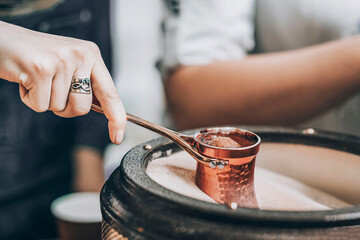 Woman's Hand Crafting Coffee in the Sands with a Steel Turkish Coffee Pot
