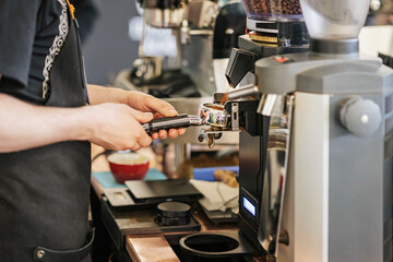 Expert Barista Crafting Espresso Excellence in Coffee Shop, grinding freshly roasted coffee in...