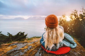 Woman relaxing outdoor bivouac with camping gear summer vacations girl hiking solo enjoying sea view active tourism tourist exploring Norway adventure healthy lifestyle trip sustainable tourism - obrazy, fototapety, plakaty