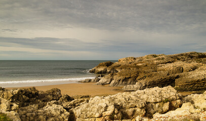 Fototapeta na wymiar Cantabria, small wave-cut beach Playa del Bocal, light sand and eroded rock cliffs 