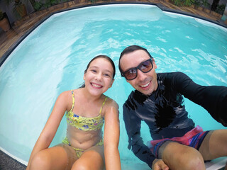 pai e filha se divertindo em água de piscina nas férias viagem de verão 