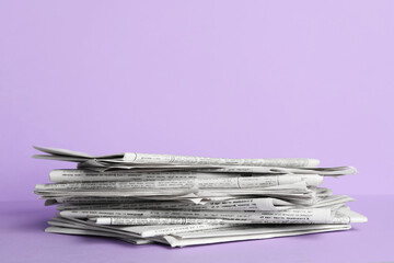 Stack of newspapers on light violet background, space for text. Journalist's work