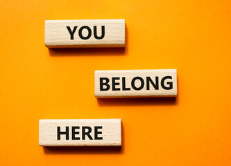 You belong here symbol. Wooden blocks with words You belong here. Beautiful orange background. Business and You belong here concept. Copy space.