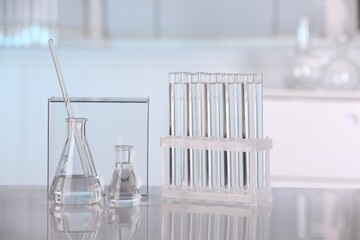 Laboratory analysis. Glass flasks, test tubes and stirring rod on white table indoors