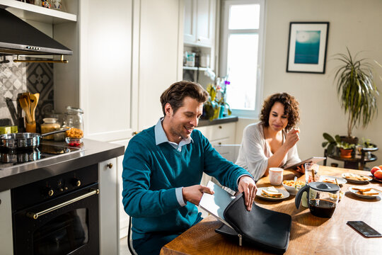 Young man getting ready for work in the kitchen with woman