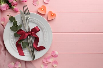 Place setting with heart shaped candles and bouquet of roses for romantic dinner on pink wooden table, flat lay. Space for text
