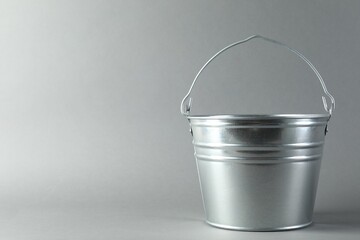 One shiny metal bucket on light grey background. Space for text