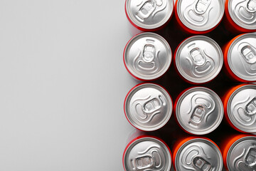 Energy drink in cans on grey background, top view. Space for text