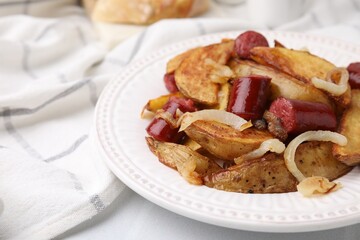Delicious baked potato with thin dry smoked sausages and onion on table, closeup
