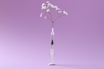 Cosmetology. Medical syringe and gypsophila on violet background