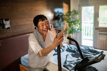 Young Asian woman on a exercise bike in her bedroom at home