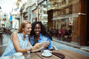 Two young women taking selfie in street cafe