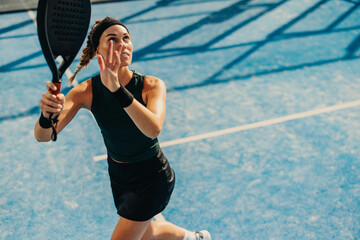 Female athlete receiving a high lob in a padel tennis game