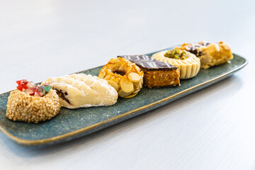 Horizontal photo assorted gourmet arabic pastries on elongated plate. Food and culture concept.
