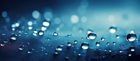 Numerous clear water droplets are dispersed across a glass surface, reflecting light and creating a sparkling effect. The drops appear round and symmetrical, enhancing the visual appeal of the scene.