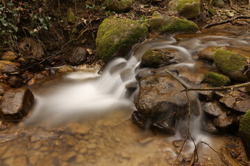 Naklejka na ściany i meble long exposure picture of the flowing water at a small waterfall