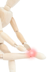 A wooden drawing mannequin on a white background with pain in the foot. Discomfort when walking.