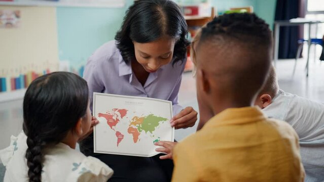 Female primary or elementary school teacher showing map to students sitting on floor in multi-cultural classroom in geography lesson - shot in slow motion