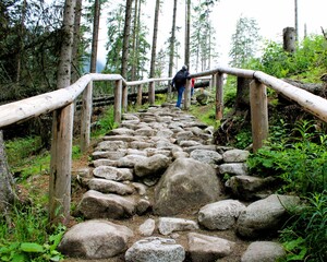 a stone-built mountain path with wooden balustrades along the sides of the path