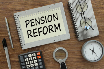 pension reform gray notepad with text on a torn page. a table clock