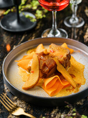 Holiday baked meat with sweet sauce  and pear on marble background with wine glasses, decoration. Holiday healthy food, top view