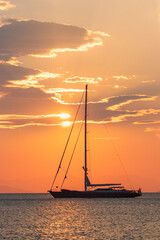 Luxury catamaran sailing vessel with dramatic sky at sunrise.