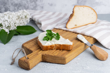 Cream cheese with herbs and seasoning on slice of fresh crunchy rye bread with cheese knife nearby