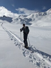 Ski tourer is out and about in a beautiful mountain landscape. Ski mountaineering in the beautiful Swiss mountains. beautiful deep snow trail towards the summit. High quality photo.