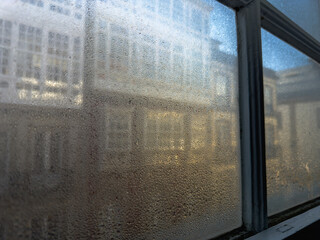 Morning Dew: Glistening Condensation on a Windowpane with a Glimpse of the Urban Beyond