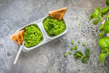 Pea puree with basil and roasted bread on rustic gray background, top view