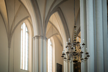 Chandelier with modern lightbulbs inside a gothic church with tall roof and concrete pillars....